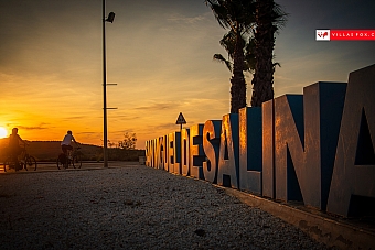 San Miguel de Salinas cyclists and town sign at sunset